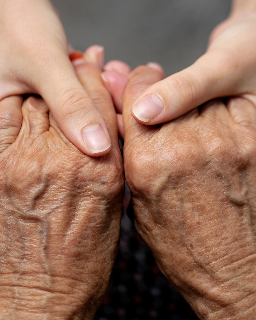 An older patient's hands held by their provider